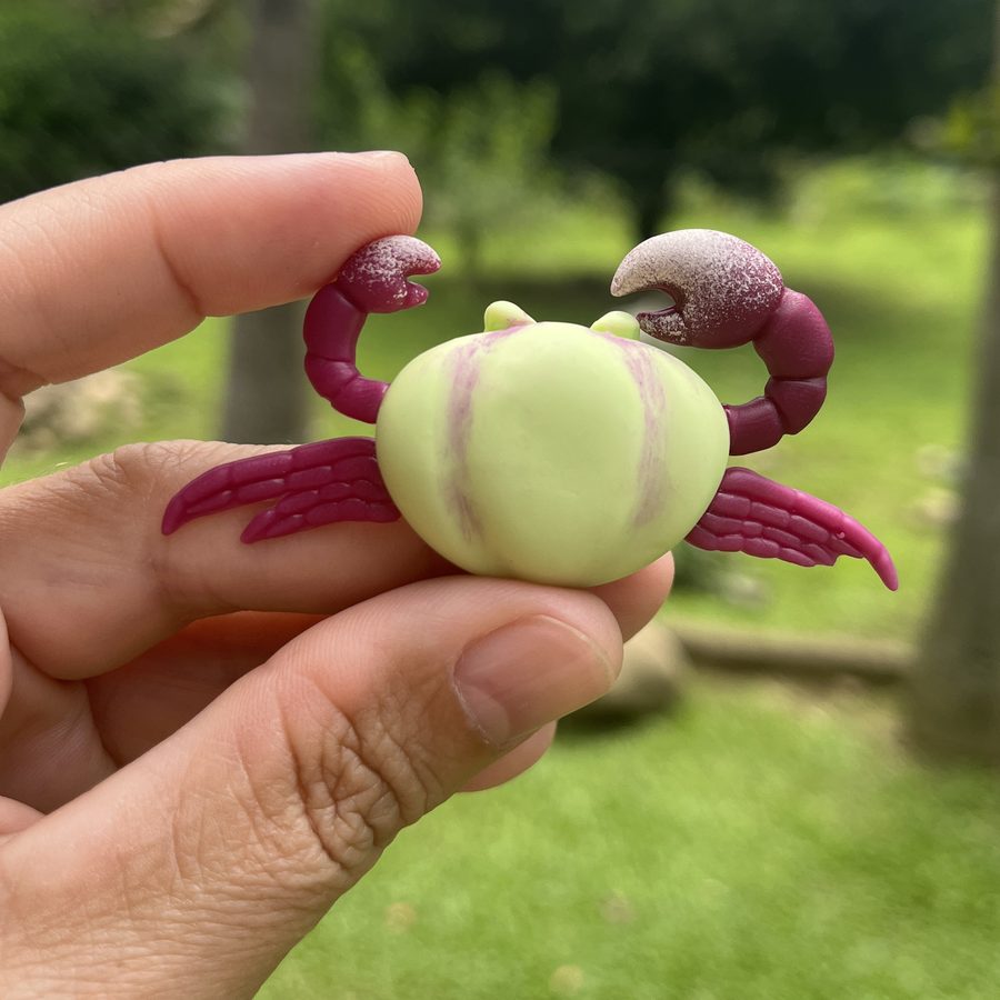 Peça de caranguejo-uçá em biscuit modelada à mão, segurada na mão.