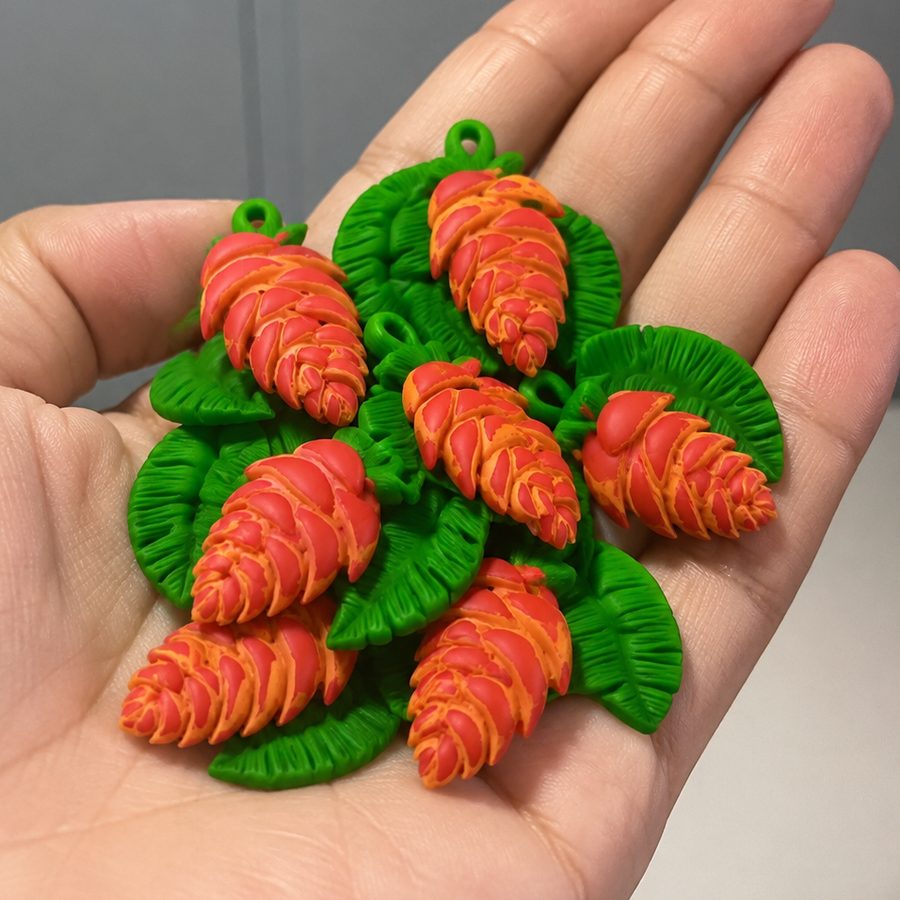 Peça de helicônia em biscuit modelada à mão, segurada na mão.
