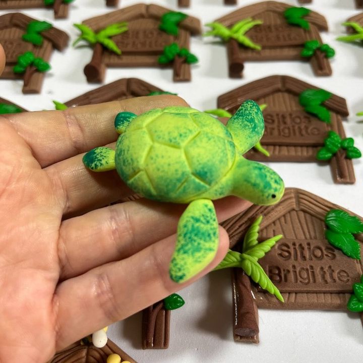 Peça de tartaruga-verde em biscuit modelada à mão, segurada na mão.