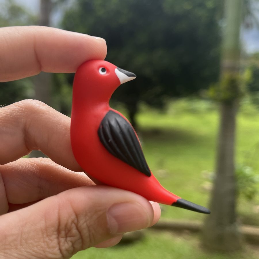 Peça de tiê-sangue em biscuit modelada à mão, segurada na mão.