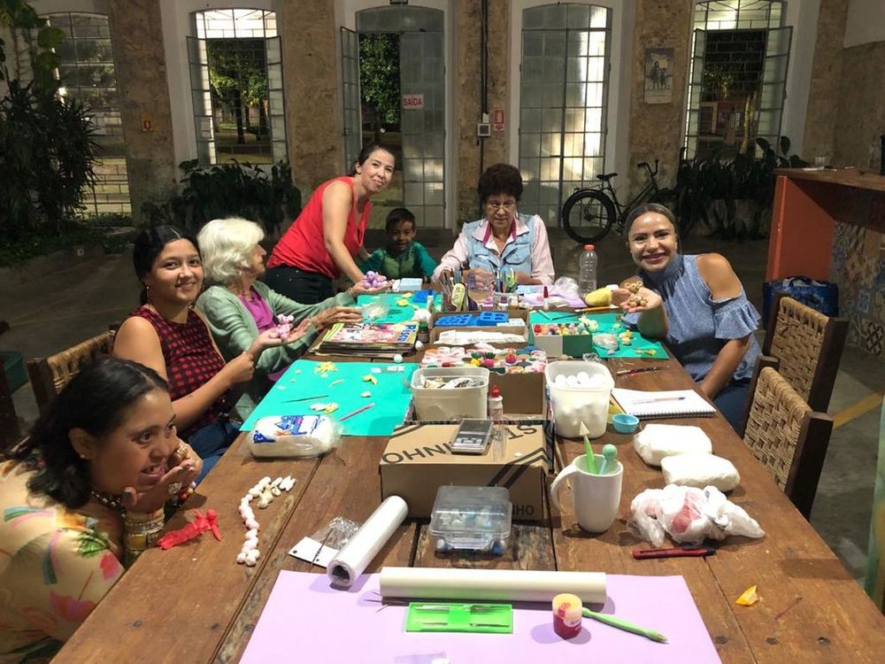 Mulheres da rede de produtoras reunidas ao redor de uma mesa de trabalho, modelando peças de biscuit durante uma capacitação em Antonina.